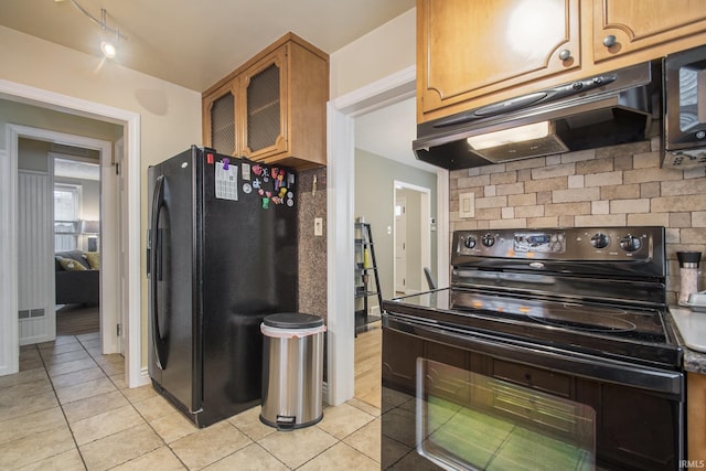 kitchen featuring light tile patterned floors, backsplash, and black appliances