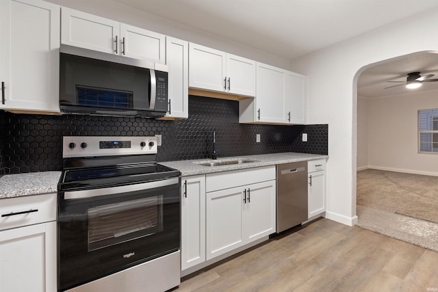 kitchen featuring white cabinetry, ceiling fan, stainless steel appliances, light stone counters, and sink