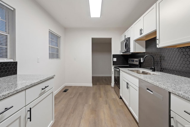 kitchen featuring light stone counters, sink, white cabinets, and stainless steel appliances