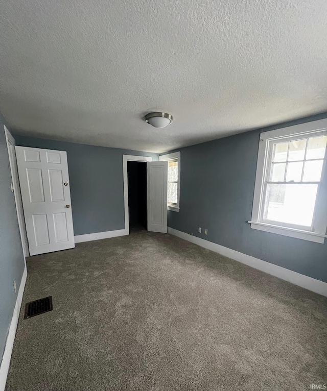 unfurnished bedroom featuring a textured ceiling and dark carpet