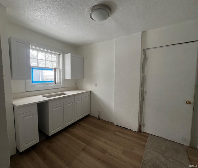 kitchen featuring white cabinets, dark hardwood / wood-style flooring, sink, and a textured ceiling