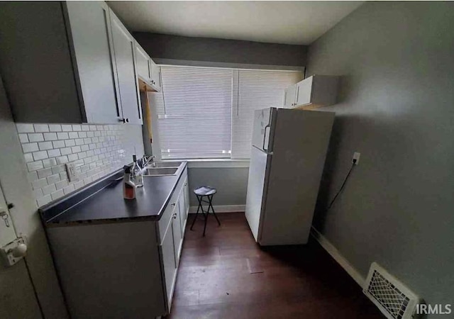 kitchen featuring white cabinets, decorative backsplash, sink, and stainless steel refrigerator