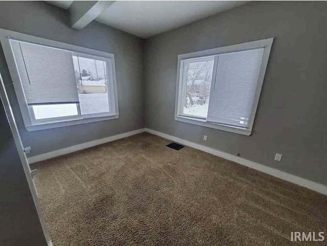 unfurnished room with carpet flooring and beam ceiling