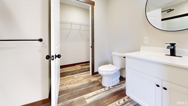 bathroom with vanity, toilet, wood finished floors, and baseboards