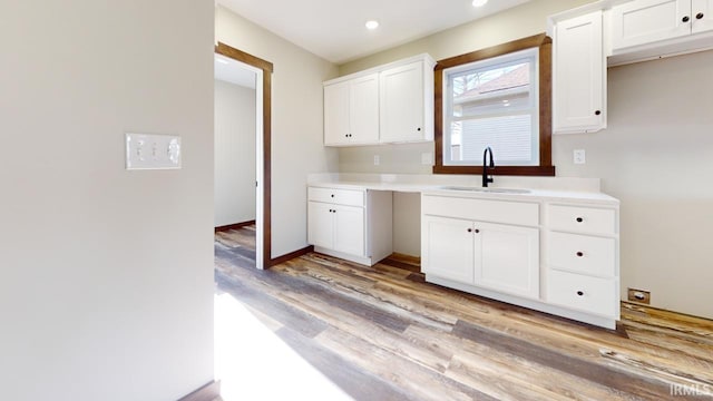 kitchen with light countertops, recessed lighting, light wood-style flooring, white cabinets, and a sink