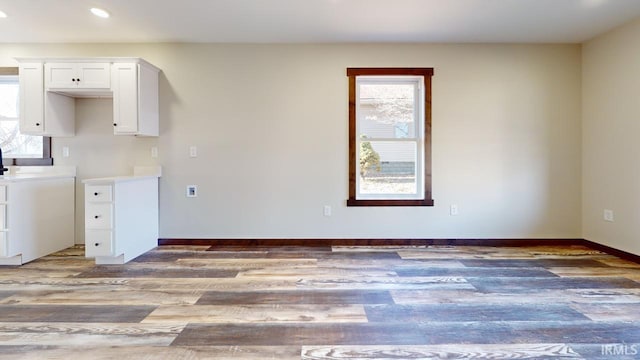 kitchen featuring recessed lighting, white cabinetry, light wood-type flooring, and baseboards