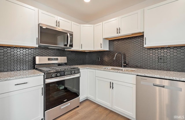 kitchen featuring sink, backsplash, white cabinets, and appliances with stainless steel finishes