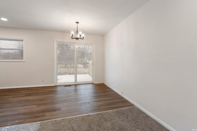 unfurnished room featuring dark wood-type flooring and a notable chandelier