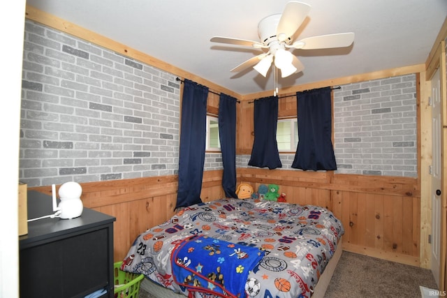 carpeted bedroom with ceiling fan, brick wall, and wooden walls