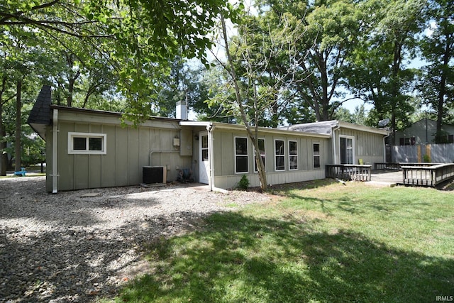 back of property with a deck, a yard, and central AC