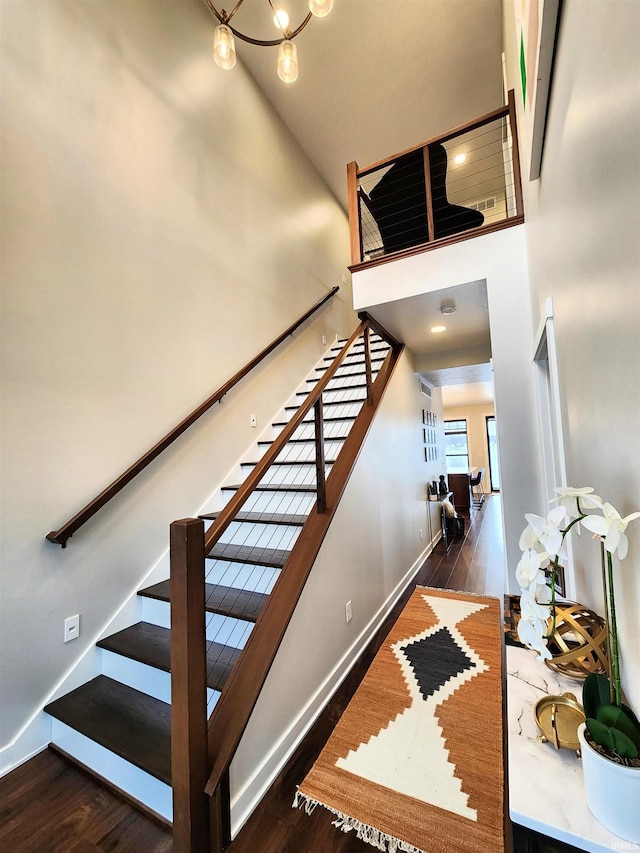 stairway featuring hardwood / wood-style flooring, a notable chandelier, and a high ceiling