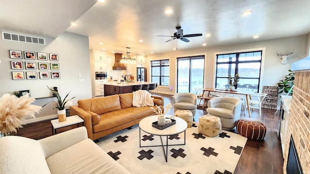 living room featuring a brick fireplace, ceiling fan with notable chandelier, and light wood-type flooring