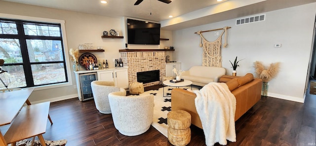 living room featuring ceiling fan, a brick fireplace, wine cooler, dark hardwood / wood-style floors, and bar area