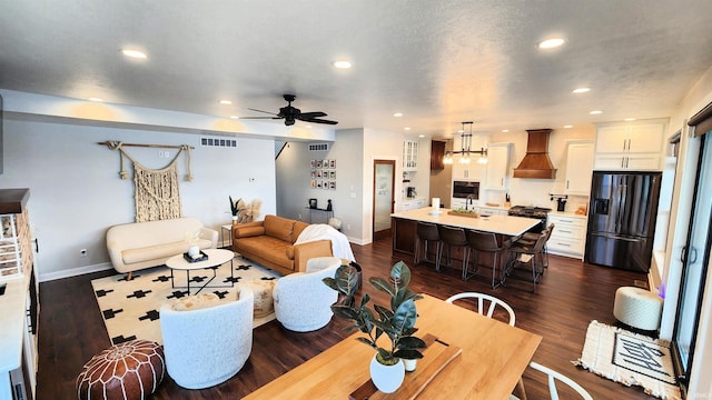 living room with sink, dark wood-type flooring, and ceiling fan with notable chandelier