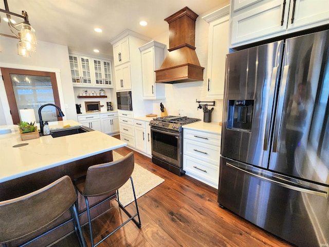 kitchen with sink, hanging light fixtures, premium range hood, white cabinets, and black appliances