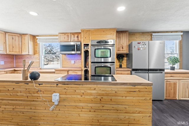 kitchen with appliances with stainless steel finishes, light brown cabinets, a textured ceiling, and dark hardwood / wood-style floors