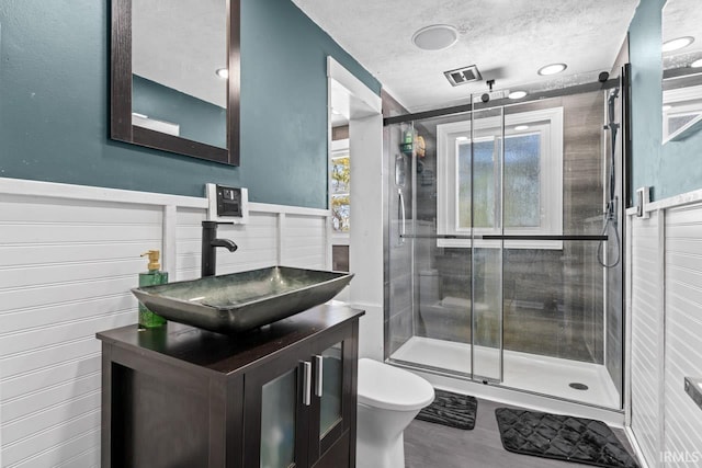 bathroom featuring toilet, vanity, a textured ceiling, and walk in shower