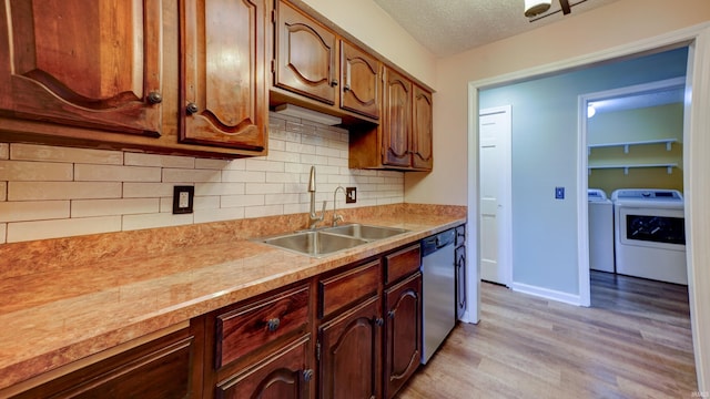 kitchen featuring light wood-type flooring, a textured ceiling, sink, dishwasher, and washing machine and dryer