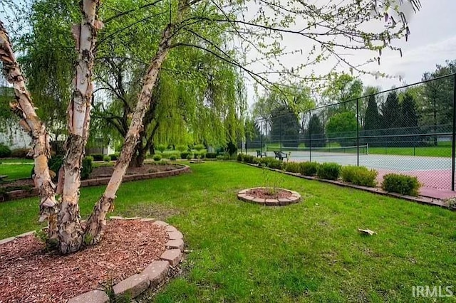 view of community featuring a yard and tennis court