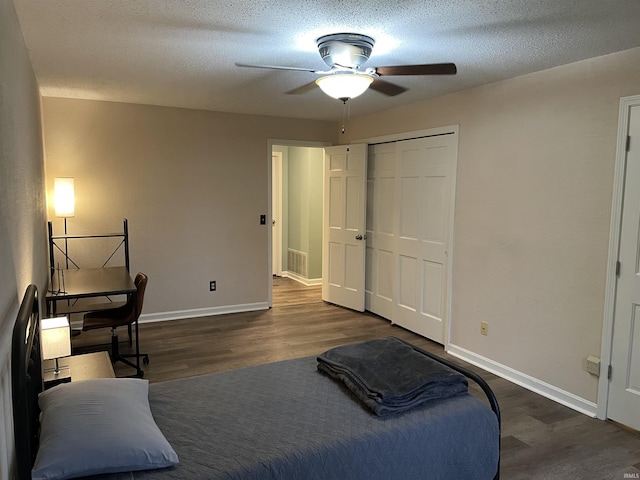 bedroom with a textured ceiling, ceiling fan, dark wood-type flooring, and a closet