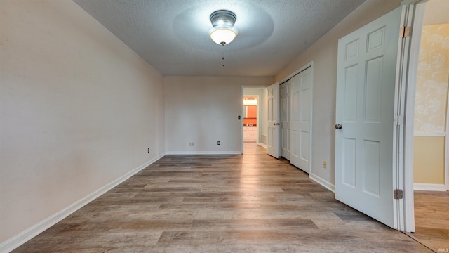 empty room with light wood-type flooring and a textured ceiling