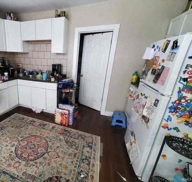 kitchen with backsplash, white cabinets, sink, white fridge, and dark hardwood / wood-style flooring