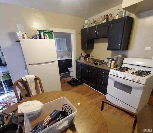 kitchen with light wood-type flooring, white appliances, and sink