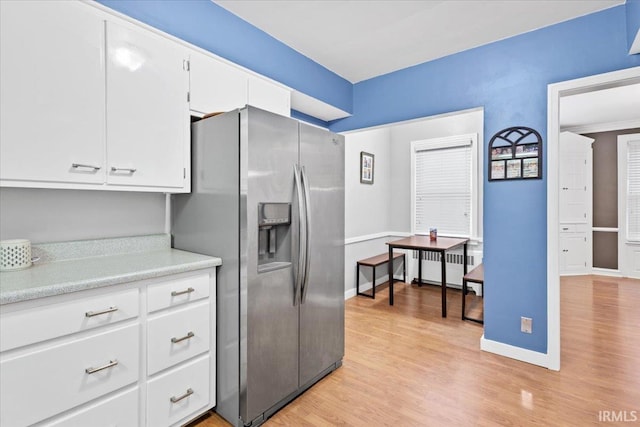 kitchen with white cabinets, light wood-type flooring, and stainless steel fridge with ice dispenser