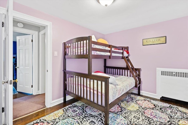 bedroom with dark hardwood / wood-style flooring and radiator