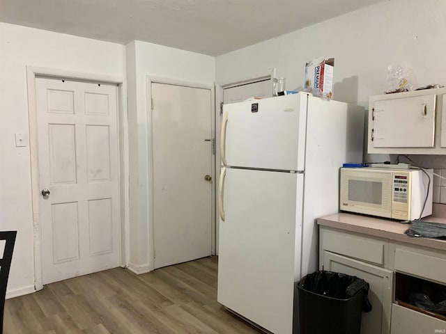 kitchen featuring white cabinets, light hardwood / wood-style floors, and white appliances