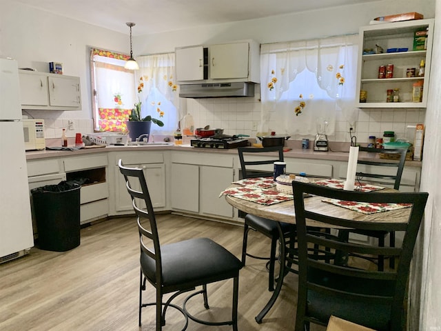 kitchen featuring white cabinets, decorative light fixtures, backsplash, and light hardwood / wood-style flooring