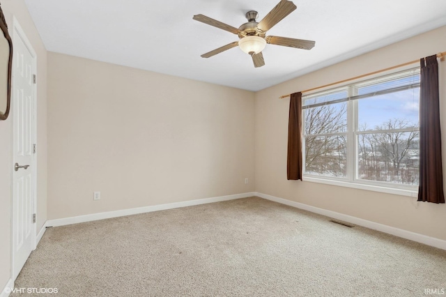 spare room with carpet floors, visible vents, ceiling fan, and baseboards