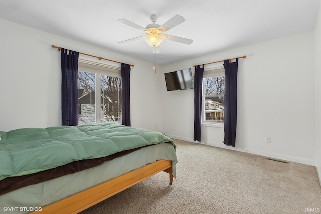 carpeted bedroom featuring a ceiling fan, visible vents, and baseboards