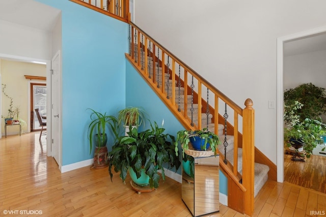 stairs with baseboards, a towering ceiling, and hardwood / wood-style floors