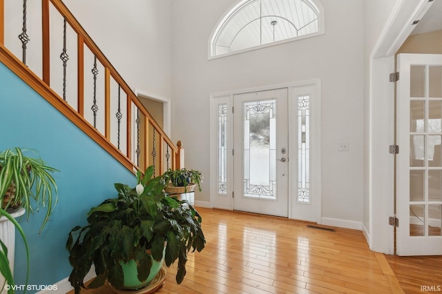 foyer featuring light wood-type flooring, baseboards, stairs, and visible vents