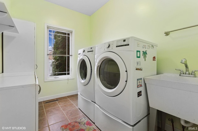 clothes washing area featuring light tile patterned flooring, laundry area, separate washer and dryer, a sink, and visible vents