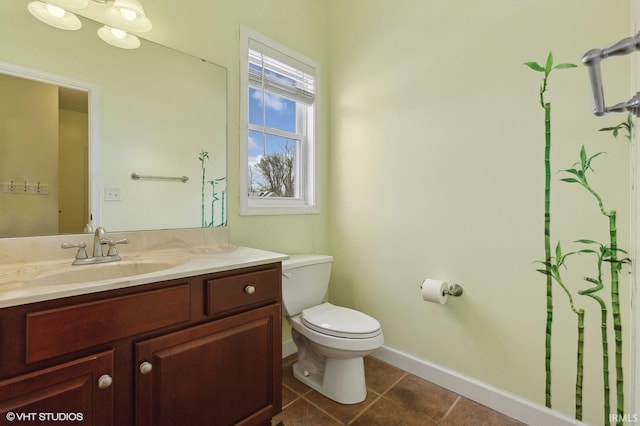 bathroom with tile patterned flooring, baseboards, vanity, and toilet