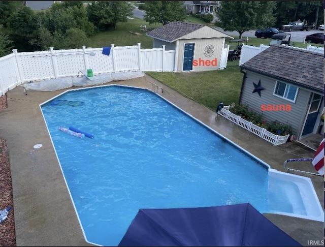 view of swimming pool with a fenced in pool, an outbuilding, a yard, and fence