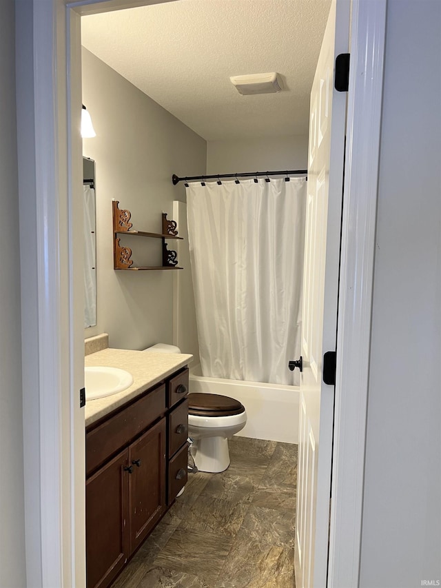 full bathroom featuring shower / bathtub combination with curtain, vanity, a textured ceiling, and toilet