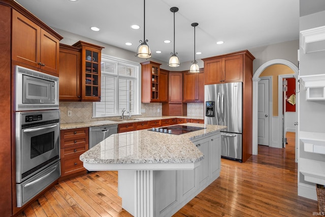 kitchen with a breakfast bar, a center island, light stone countertops, tasteful backsplash, and stainless steel appliances