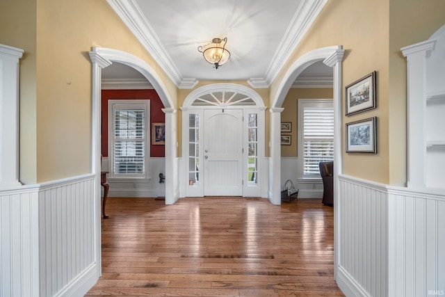 foyer entrance featuring dark hardwood / wood-style floors, ornamental molding, and ornate columns