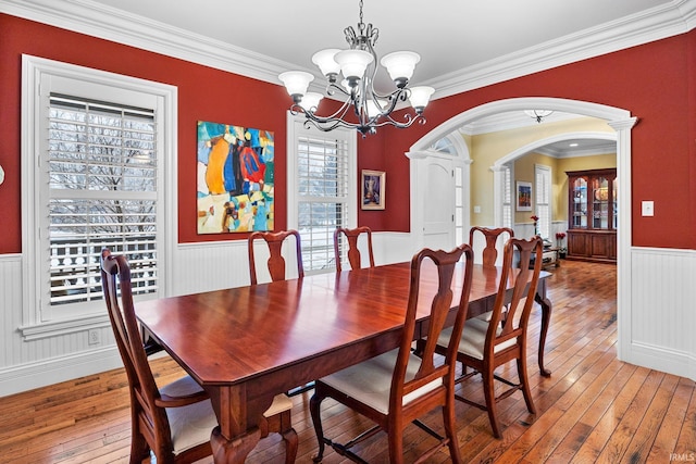 dining area with hardwood / wood-style flooring, an inviting chandelier, and ornamental molding