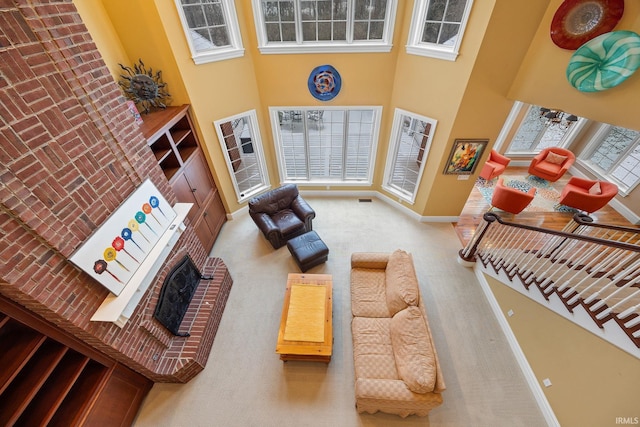 living room with ceiling fan, carpet, a high ceiling, and a brick fireplace