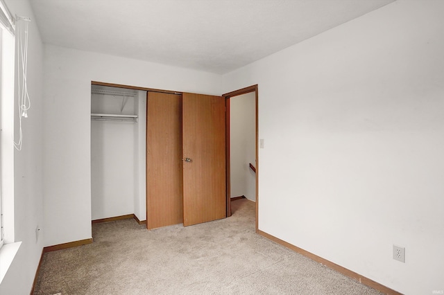 unfurnished bedroom featuring light colored carpet and a closet