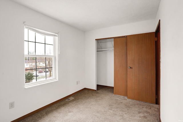 unfurnished bedroom with light carpet and a closet