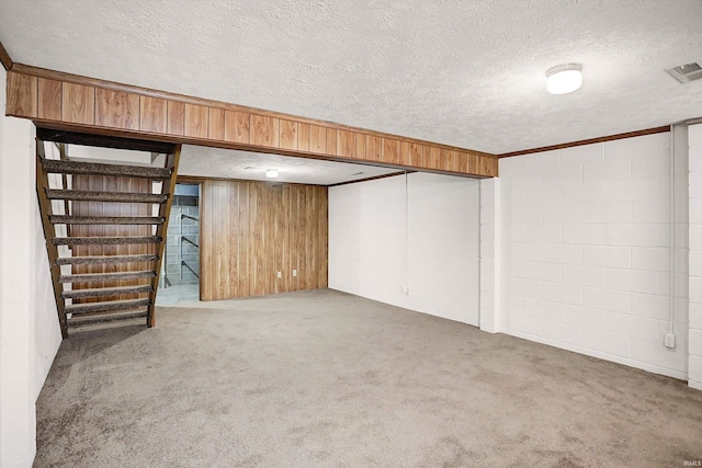 basement featuring wooden walls, carpet floors, and a textured ceiling