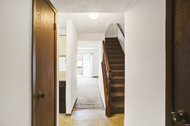 corridor with light carpet and a textured ceiling