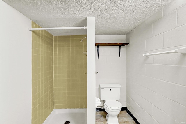 bathroom with a tile shower, a textured ceiling, and toilet