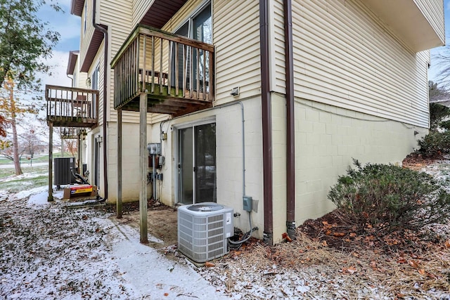 snow covered property with a balcony and central AC unit