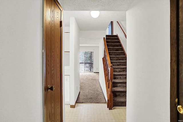 hall with a textured ceiling and light carpet